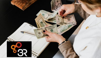 Someone holding cash with notepad and pen