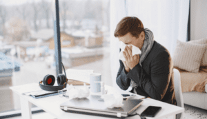 Man blowing his nose at his desk