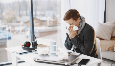 Man blowing his nose at his desk